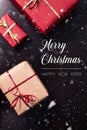 Merry christmas and happy new year greeting card with white lettering, snowflakes and craft paper presents with ribbon on dark Royalty Free Stock Photo