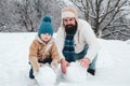 Merry Christmas and Happy New Year. Happy father and son making snowman in the snow. Handmade funny snow man. Winter Royalty Free Stock Photo