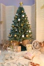Merry Christmas and Happy New Year living room interior with decorated firtree, golden garland lights, star, white candles Royalty Free Stock Photo