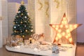 Merry Christmas and Happy New Year living room interior with decorated firtree, golden garland lights, star, white candles Royalty Free Stock Photo