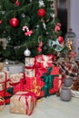 Merry Christmas and Happy New Year presents standing under the decorated fir-tree with red bulbs, toys and bows. Royalty Free Stock Photo