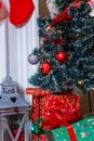 Merry Christmas and Happy New Year presents standing under the decorated fir-tree with red bulbs, toys and bows. Winter holidays Royalty Free Stock Photo