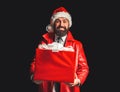 Merry Christmas and Happy New Year. Santa claus with red Christmas gift box. Bearded modern santa on black background