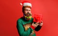 Merry Christmas. Happy New Year. Serious Santa man with Christmas gift. Bearded man in Santa hat with present box Royalty Free Stock Photo