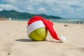 Merry Christmas and Happy New Year on the summer beach. Coconut in santa hat. Palms and blue sky on the background Royalty Free Stock Photo