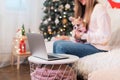 Merry Christmas and happy new year. Woman and puppy dog in sweater having a video chat on laptop, enjoy winter holidays