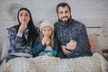 Merry Christmas and Happy New Year . Young family celebrating holiday at home. The Father is holding the remote from the Royalty Free Stock Photo