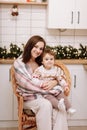 Merry Christmas and Happy New Years Holidays. Young mother hugging and kissing her baby daughter, sitting and relaxing Royalty Free Stock Photo