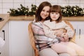 Merry Christmas and Happy New Years Holidays. Young mother hugging and kissing her baby daughter, sitting and relaxing Royalty Free Stock Photo