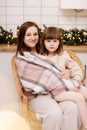 Merry Christmas and Happy New Years Holidays. Young mother hugging and kissing her baby daughter, sitting and relaxing Royalty Free Stock Photo