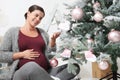 Merry christmas, happy pregnant woman prepare the Christmas tree, open the boxes of balls decorations in the living room