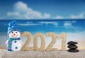 Merry Christmas. Happy snowman and lettering 2021 in sand on the beach Royalty Free Stock Photo