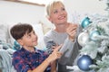 Merry christmas at home, smiling mom and son decorate tree hang decorations and balls in the living room Royalty Free Stock Photo