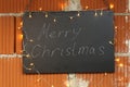 Merry Christmas inscription on the black chalkboard illuminated by garlands Royalty Free Stock Photo