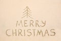 Merry Christmas inscription on wet yellow beach sand Royalty Free Stock Photo