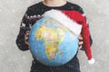 Merry Christmas. kid holding earth globe with a Santa hat Royalty Free Stock Photo