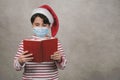 Merry Christmas,kid with medical mask Wearing Christmas Santa Claus hat reading a book