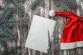 Merry Christmas letter with santa`s hat and green fir branches on old wood background. Royalty Free Stock Photo