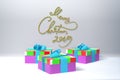 Merry Christmas 2019 lettering written by green and red spripe on white wall and three colorful present gift boxes with Royalty Free Stock Photo