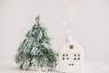 Merry Christmas. Christmas little house with golden lights bokeh and tree on white background. Happy holidays. Miniature cozy home Royalty Free Stock Photo