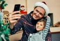Merry Christmas from me and my boy. an adorable little boy taking selfies with his father during Christmas at home.