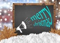 Merry Christmas and megaphone on blackboard with city leaves and snow