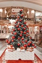 Merry Christmas, New Year in shopping mall interior decorated fir tree with garlands, orange balls and gift present boxes Royalty Free Stock Photo
