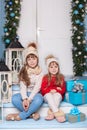 Merry Christmas! New Year. Two little girls are sitting on porch of house for Christmas. Happy children play in winter in courtyar Royalty Free Stock Photo