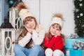 Merry Christmas! New Year. Two little girls are sitting on porch of house for Christmas. Happy children play in winter in courtyar Royalty Free Stock Photo