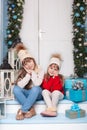 Merry Christmas! New Year. Two little girls are sitting on porch of house for Christmas. Happy children play in winter in courtyar Royalty Free Stock Photo