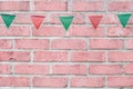 Merry Christmas Party flags bunting hanging on vintage pastel pink brick wall background on x`mas eve holiday event. Royalty Free Stock Photo