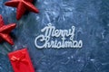 Merry Christmas phrase and gift boxes with red stars on grey background. Silver shiny Merry Christmas title. Royalty Free Stock Photo