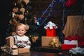 Merry Christmas. Portrait kid with gift on wooden background. Smiling child peeping from behind Christmas tree in living Royalty Free Stock Photo