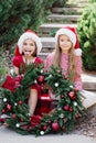 Merry Christmas. Portrait of two happy funny children girls in Santa hat with Christmas wreath Royalty Free Stock Photo