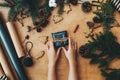 Merry Christmas, rustic flat lay. Hands holding stylish  christmas gift and pine branches, cones, gingerbread cookies,thread, Royalty Free Stock Photo