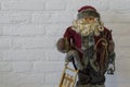 Merry christmas, a santa claus doll in closeup holding a sleigh and lantern isolated on a white brick wall background Royalty Free Stock Photo