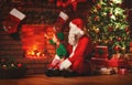 Merry Christmas! Santa Claus and little elf near fireplace Royalty Free Stock Photo