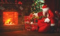 Merry Christmas! santa claus near the fireplace and tree with gi Royalty Free Stock Photo