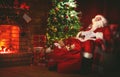 Merry Christmas! santa claus near the fireplace and tree with gi Royalty Free Stock Photo