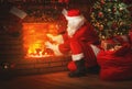 Merry Christmas! santa claus near the fireplace and tree with gi Royalty Free Stock Photo