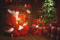 Merry Christmas! santa claus near the fireplace and tree with gi Royalty Free Stock Photo