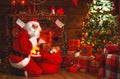 Merry Christmas! santa claus near fireplace and tree with gift Royalty Free Stock Photo