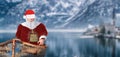 Merry christmas santa claus sailing in a baby boat on a like in a cold winter mountain landscape Royalty Free Stock Photo