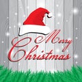 Merry Christmas and Santa`s cap on white and grey wooden background. Christmas tree on grey Lath boards background.