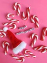 Merry Christmas sign with colorful candy canes and a Santa hat on a pink background Royalty Free Stock Photo