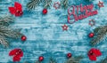 Merry Christmas sign and handmade fir toys, with red ribbon in corners,red balls, view from top, blue wooden background Royalty Free Stock Photo