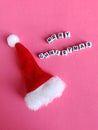 Merry Christmas sign with a Santa hat on a pink background Royalty Free Stock Photo