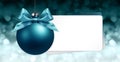 merry christmas signboard or gift card, blue ball with blue ribbon bow on blurred red xmas lights, copy space blank background Royalty Free Stock Photo