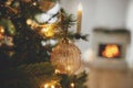 Merry Christmas! Stylish christmas gold bauble on tree close up against burning fireplace. Beautiful decorated christmas tree with Royalty Free Stock Photo