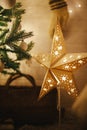 Merry Christmas! Stylish Christmas star, tree with white baubles, boho ornaments, golden lights and gifts in atmospheric evening